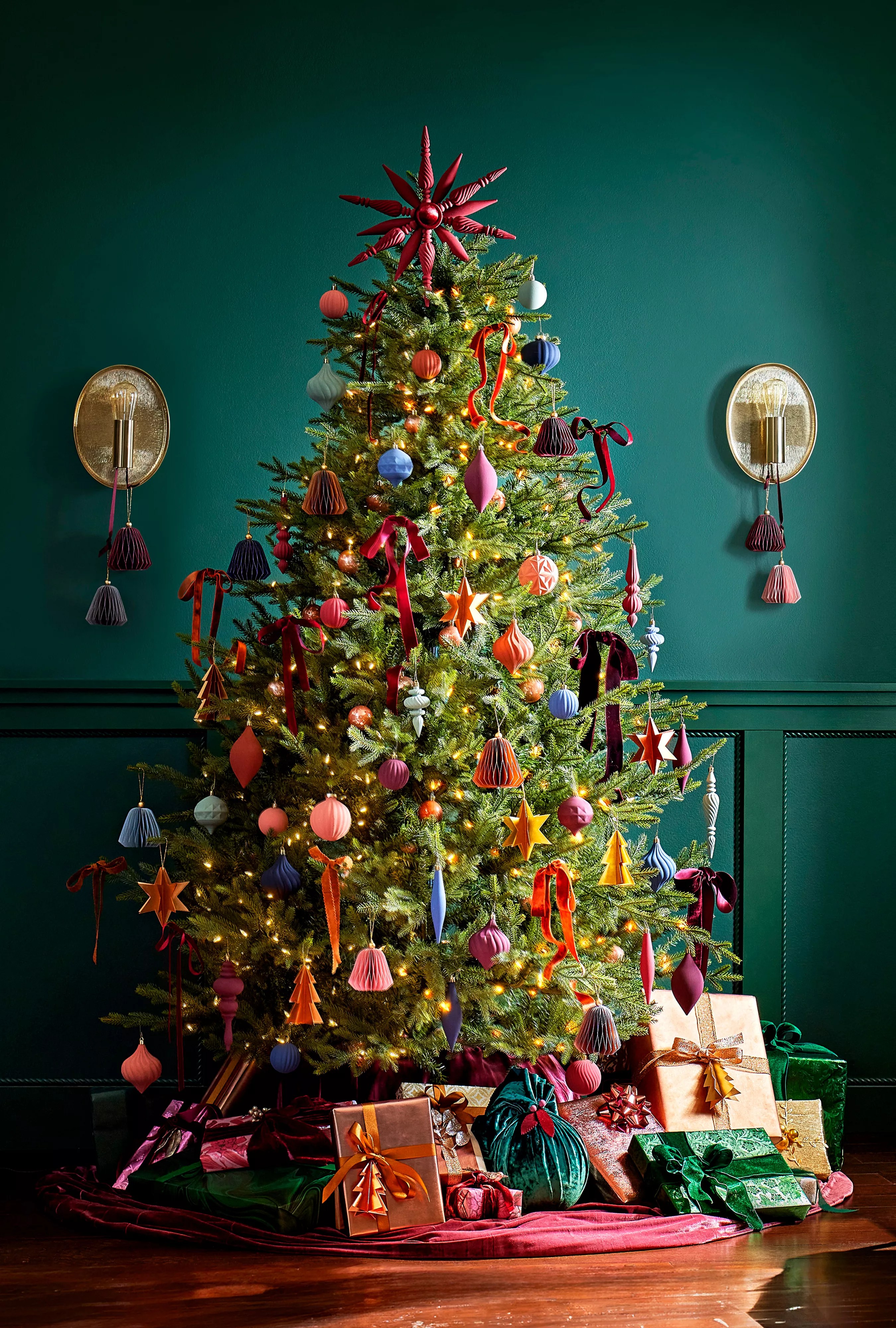 A Christmas tree in a room with dark teal colored walls.
