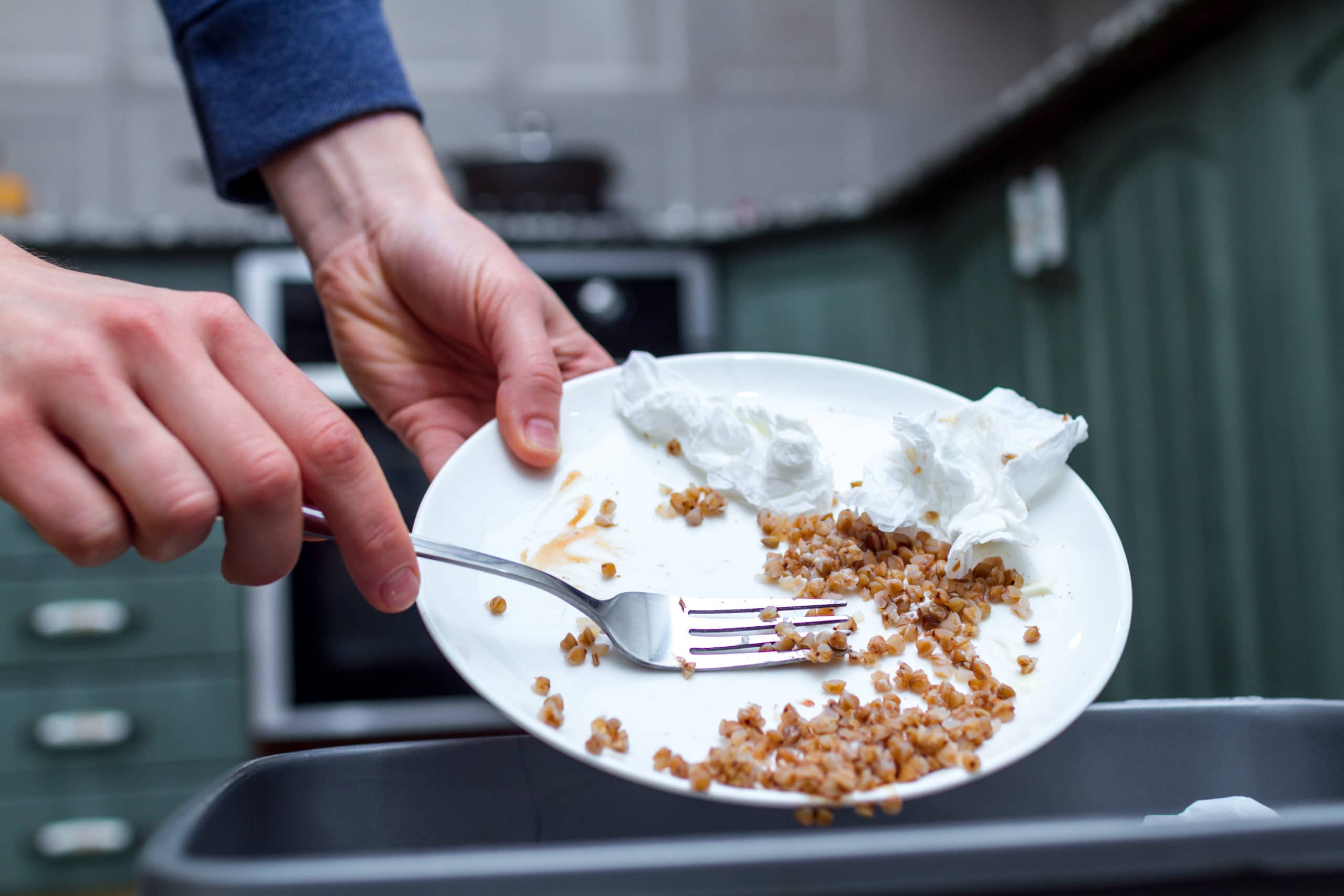 Close up of a person throwing from a plate the leftover of buckwheat to