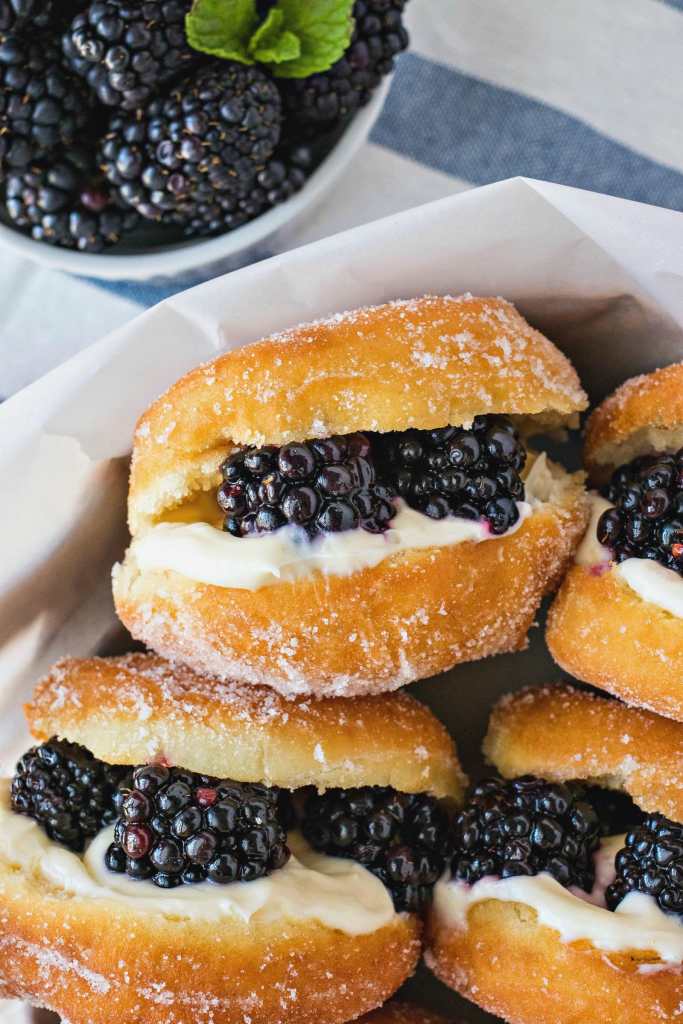 overhead shot of Blackberries & Cream Slider Doughnuts with a bowl of blackberries off to the side