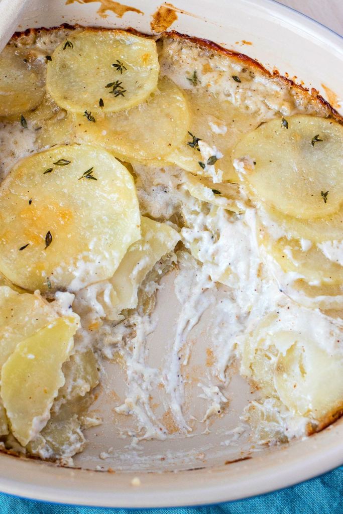 overhead shot of Parmesan & Thyme Potatoes Au Gratin in a baking dish with a spoonful taken out of the pan