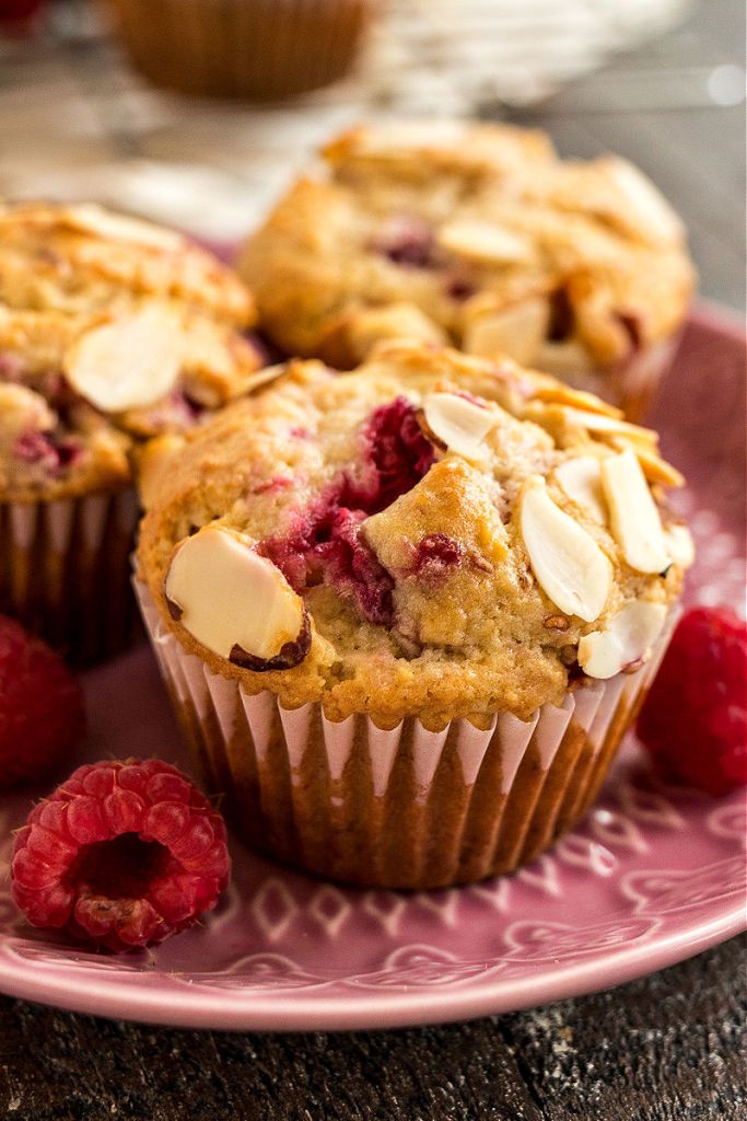 close up of raspberry almond muffin on a pink plate