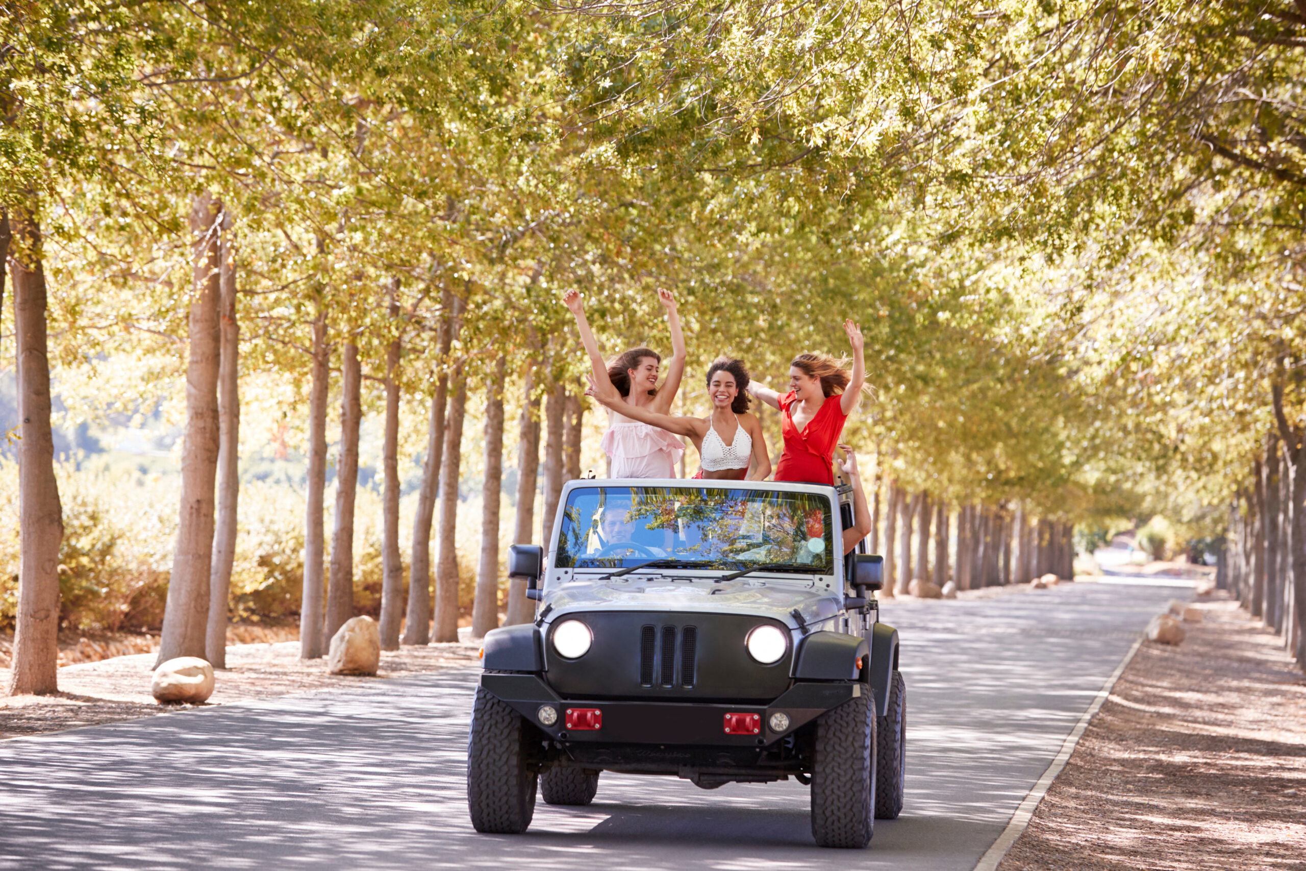 Girlfriends standing up in the back of an open top jeep Chrysler