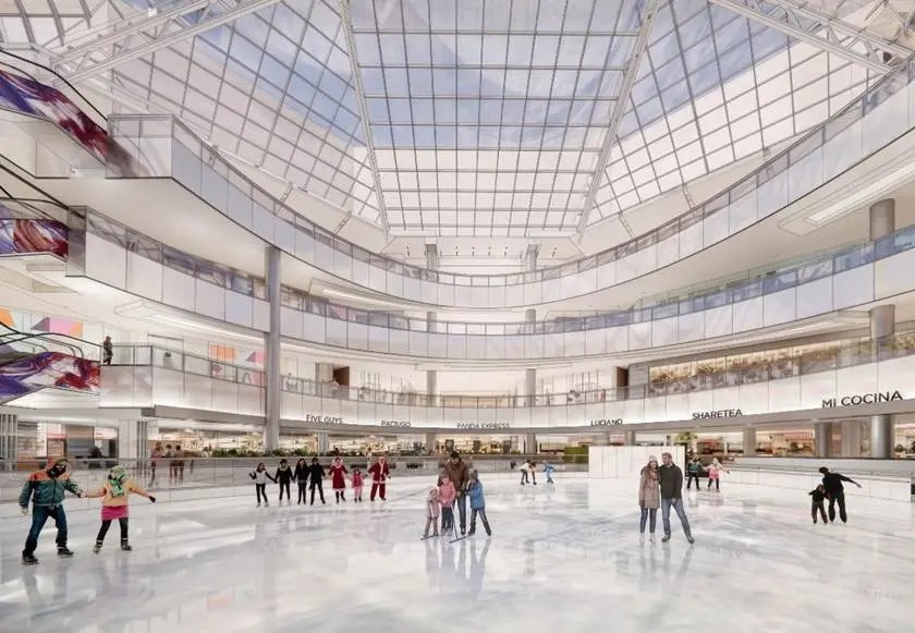 People ice skating in a bright, modern shopping mall with a glass ceiling. The atmosphere is lively and cheerful, capturing a sense of fun and community.