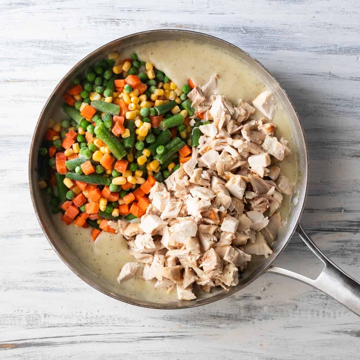 sauté pan with chicken pot pie roux, frozen mixed vegetables and shredded chicken