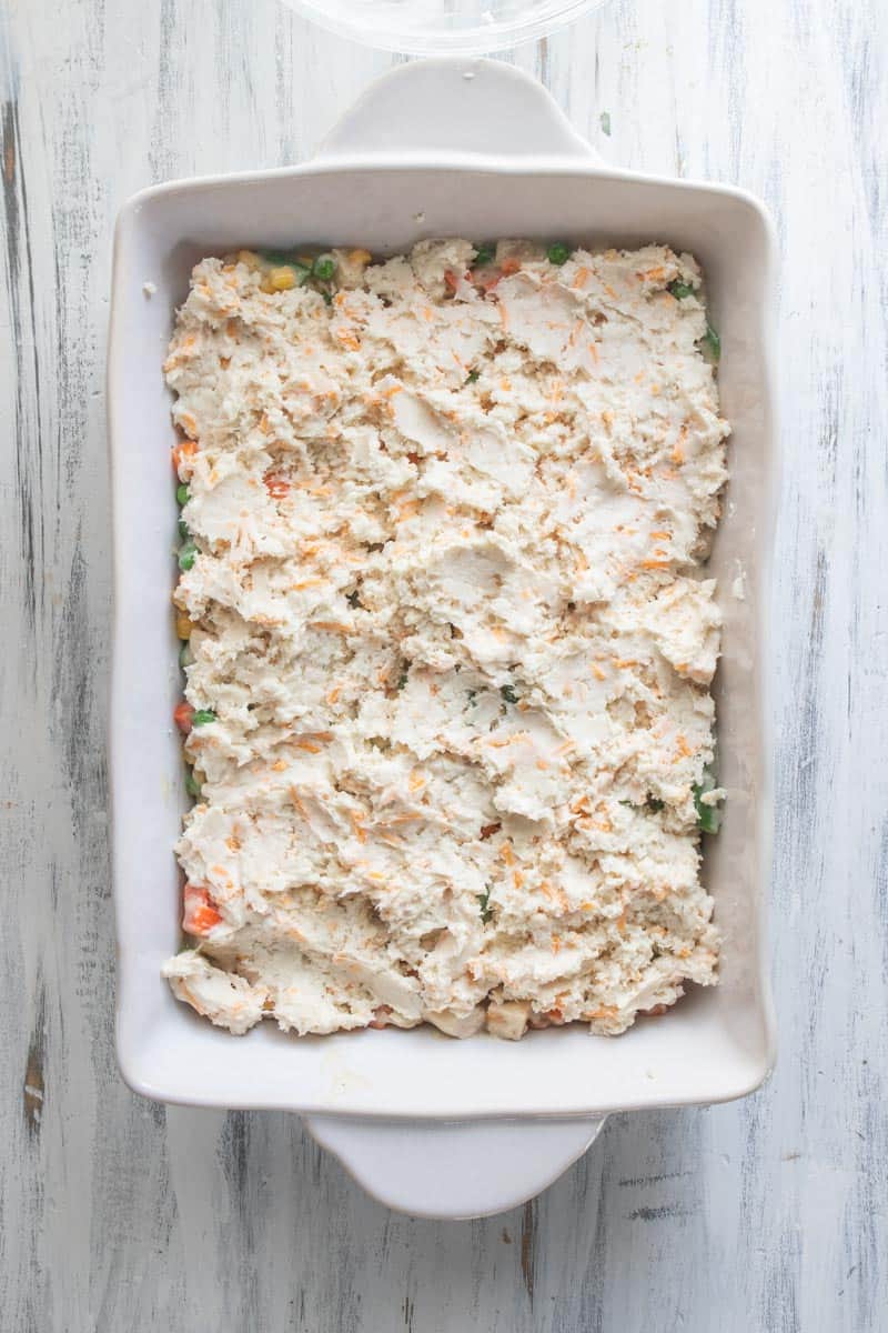 biscuit mixture on top of chicken pot pie ingredients in casserole dish