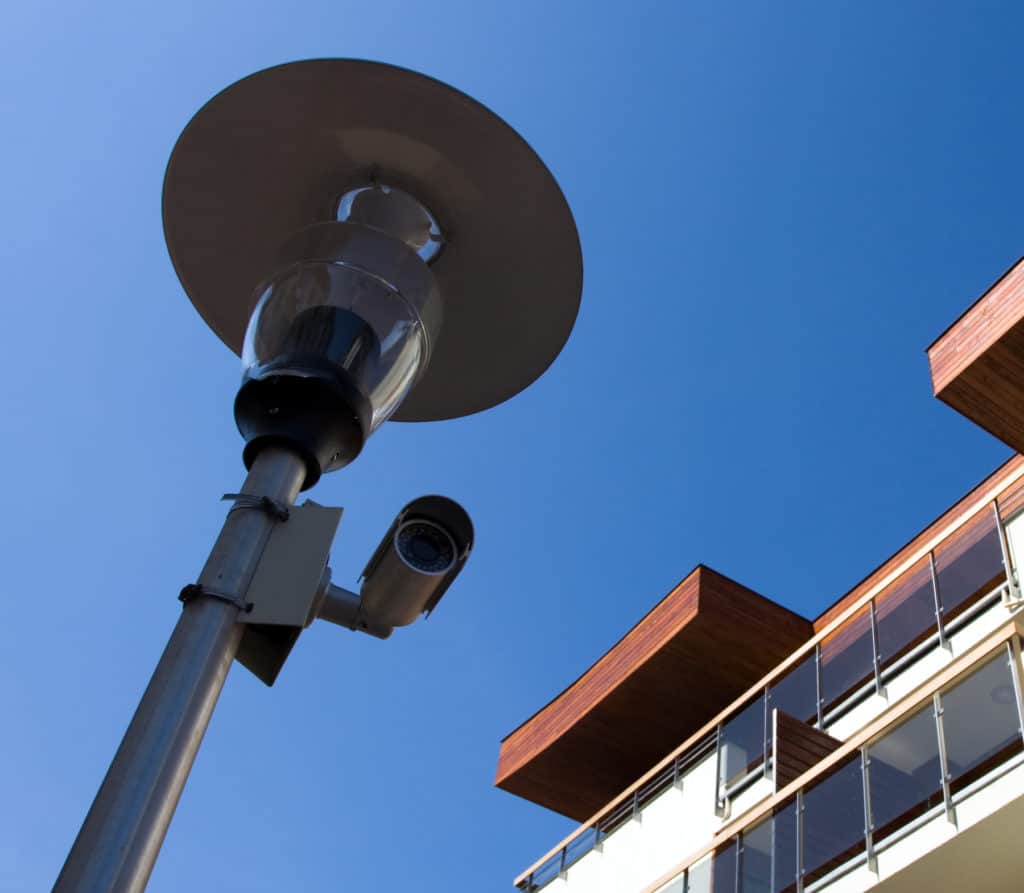 A sleek security camera attached to a lamppost is depicted. Dillard