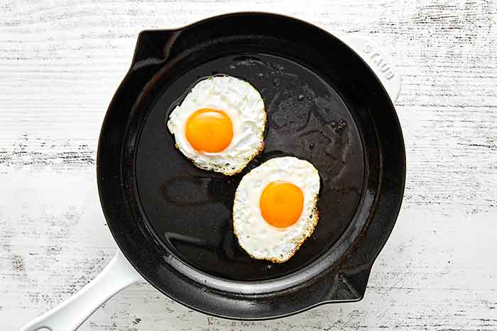 Frying eggs in a pan for huevos rancheros.