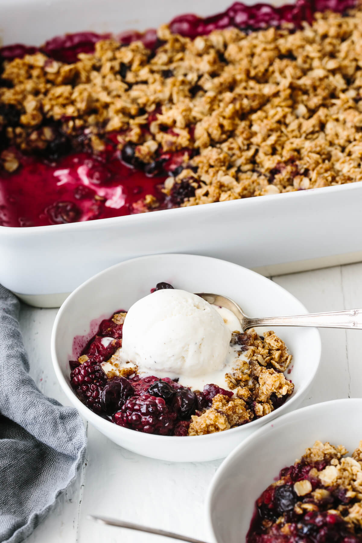 A bowl of berry crisp topped with ice cream.