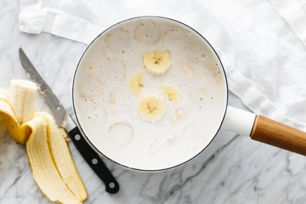 Sliced bananas in a pot of hot coconut milk.