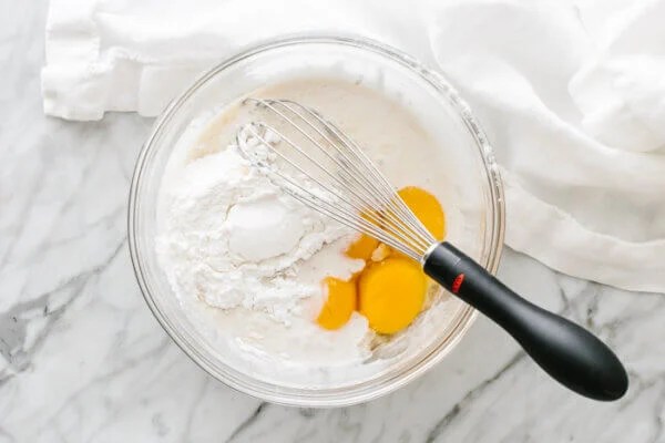 Milk, eggs, honey, and arrowroot flour in a mixing bowl.