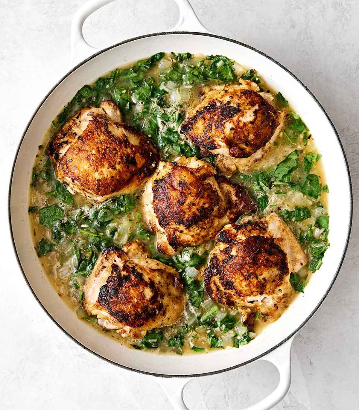This chicken and rice is an easy, one-pan weeknight dinner I can always depend on. Mediterranean chicken thighs mixed with herby rice! Simmering chicken thighs in an herby rice mixture in a pan.
