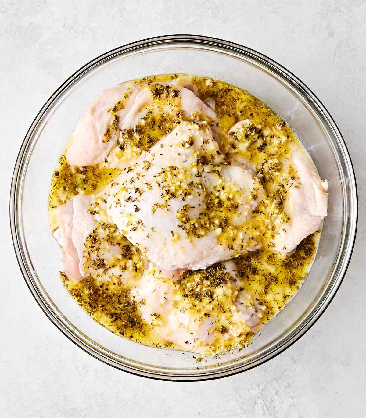 This chicken and rice is an easy, one-pan weeknight dinner I can always depend on. Mediterranean chicken thighs mixed with herby rice! Marinating chicken thighs in a bowl.