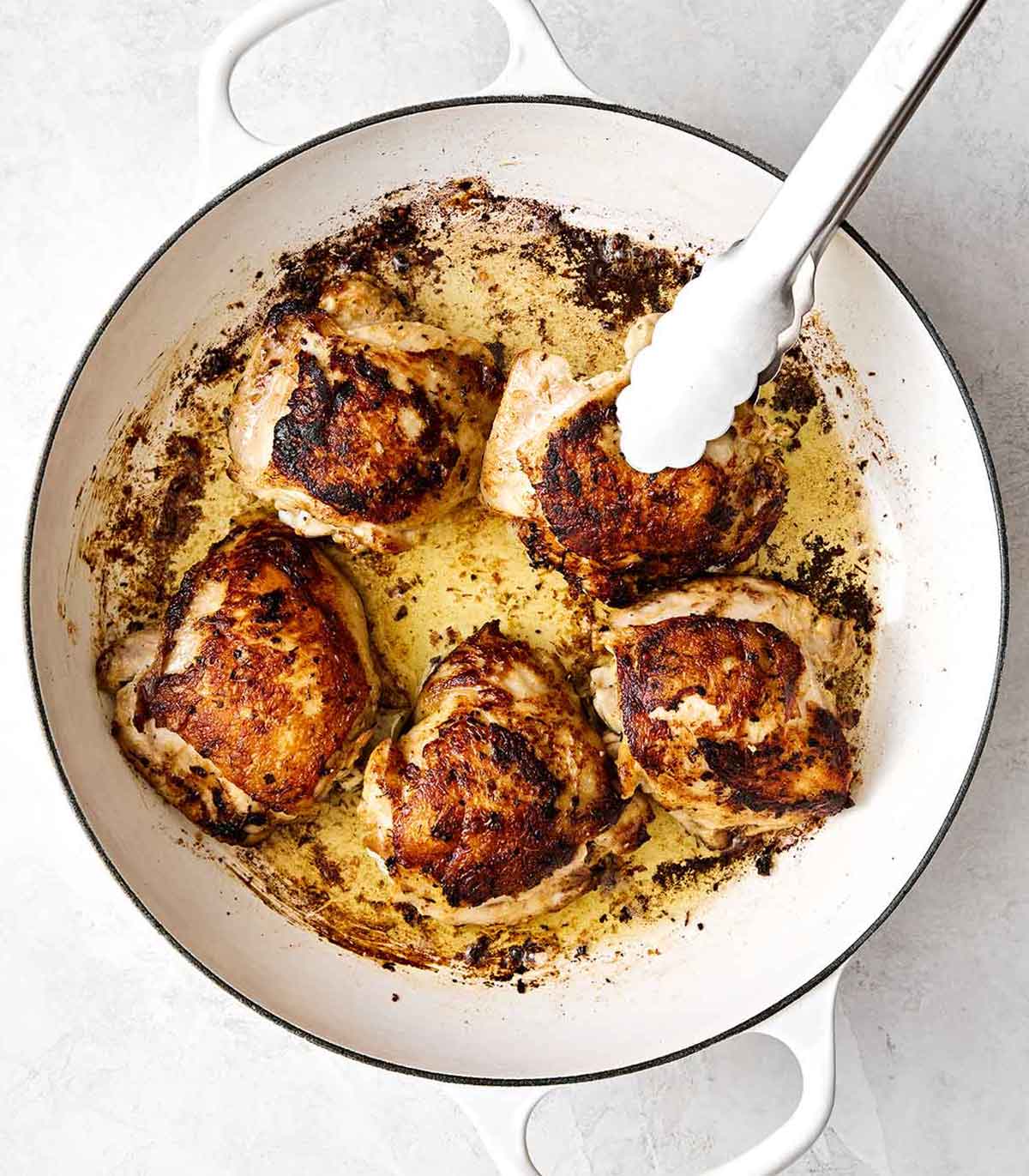 This chicken and rice is an easy, one-pan weeknight dinner I can always depend on. Mediterranean chicken thighs mixed with herby rice! Cooking chicken thighs in a pan.