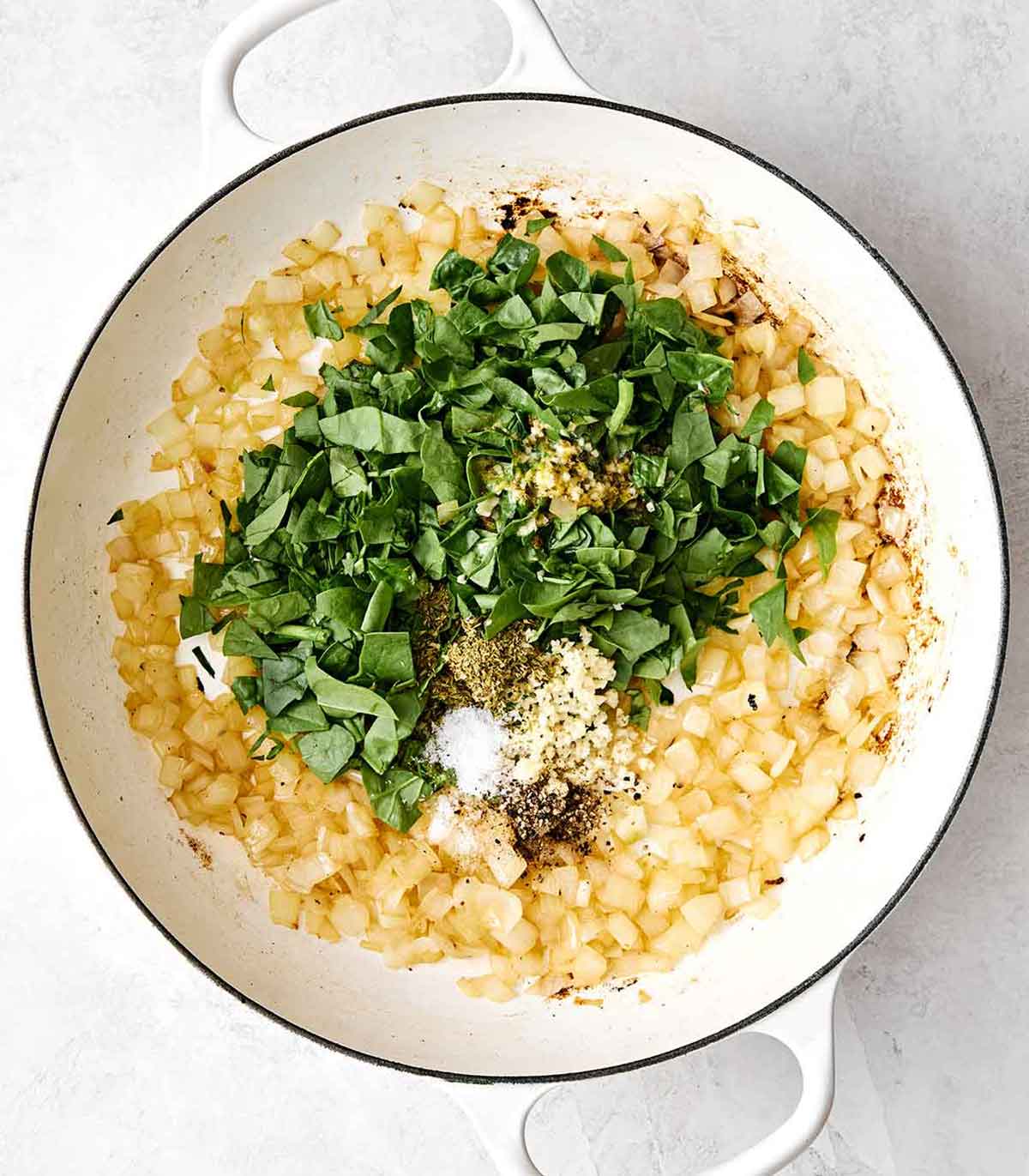 This chicken and rice is an easy, one-pan weeknight dinner I can always depend on. Mediterranean chicken thighs mixed with herby rice! Cooking onions with herbs in a pan.