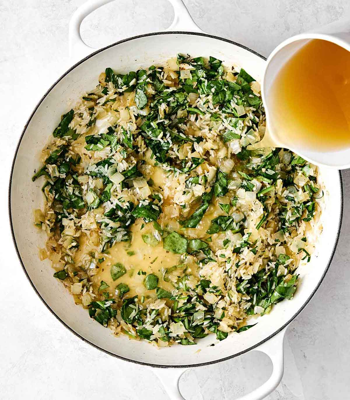 This chicken and rice is an easy, one-pan weeknight dinner I can always depend on. Mediterranean chicken thighs mixed with herby rice! Adding broth and rice to a pan.