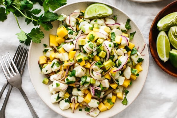 Mango halibut ceviche on a plate next to forks and cilantro.