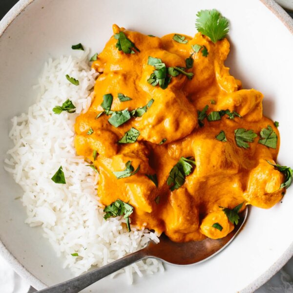 A bowl of butter chicken topped on rice.