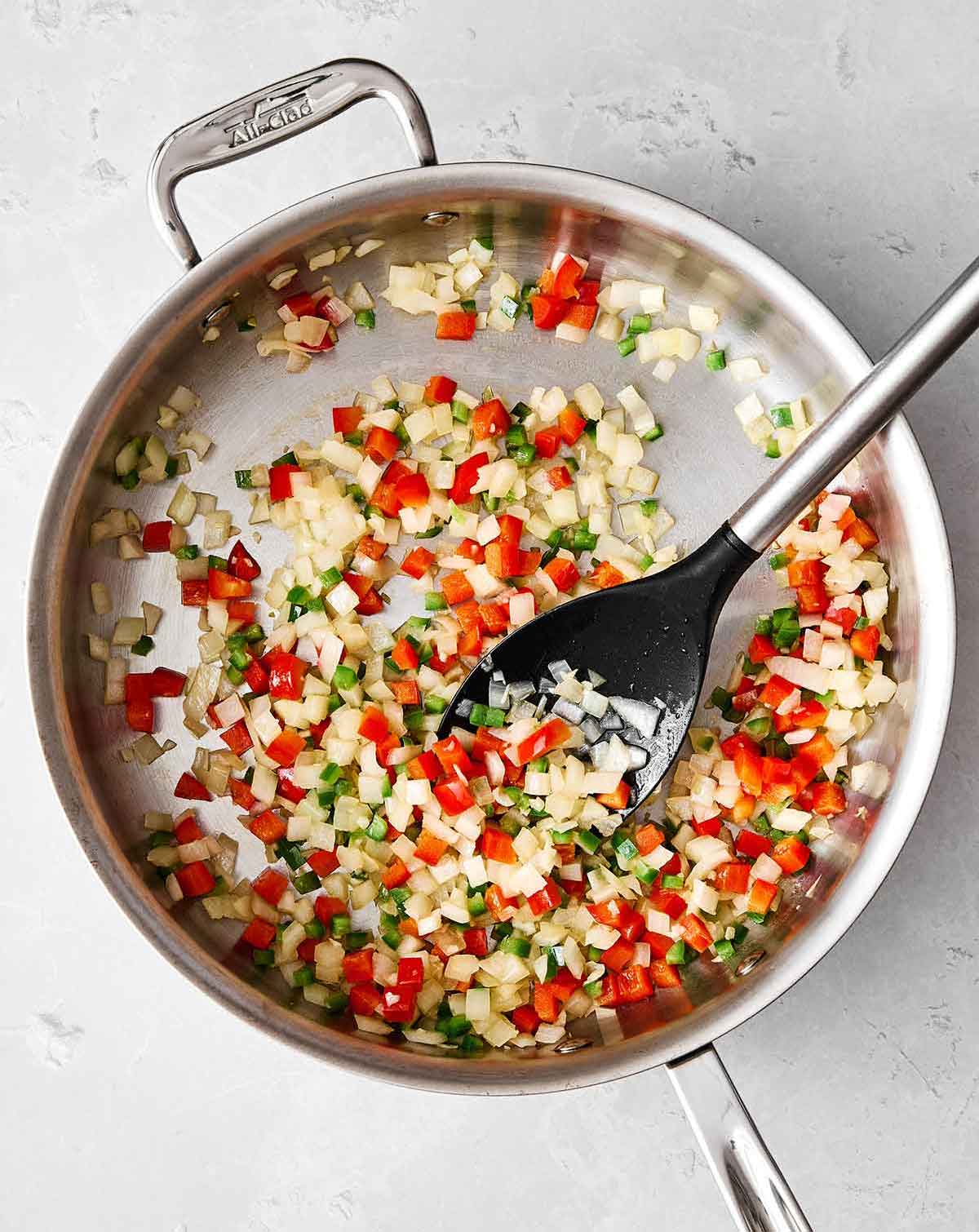 This Mexican rice is the perfect side dish for your dinner spread! It's layered with authentic flavor, really easy to make, and loved by all. Cooking veggies in a pan for Mexican rice.