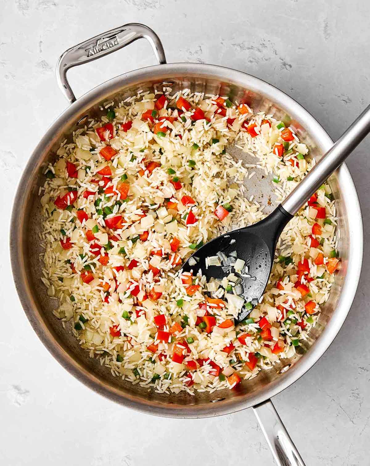 This Mexican rice is the perfect side dish for your dinner spread! It's layered with authentic flavor, really easy to make, and loved by all. Cooking rice and veggies in a pan for Mexican rice.