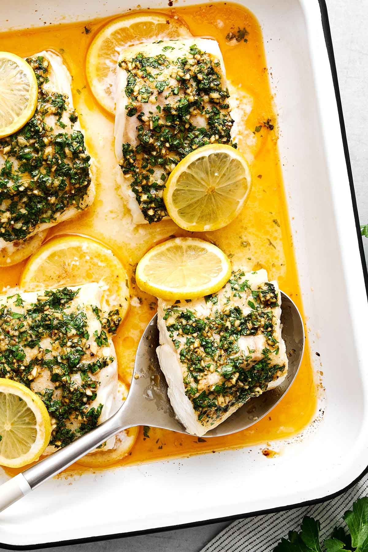 This baked cod is my foolproof recipe for flaky white fish, in under 30 minutes. A simple buttery garlic herb topping is all you need! Garlic butter herb baked cod fillets.