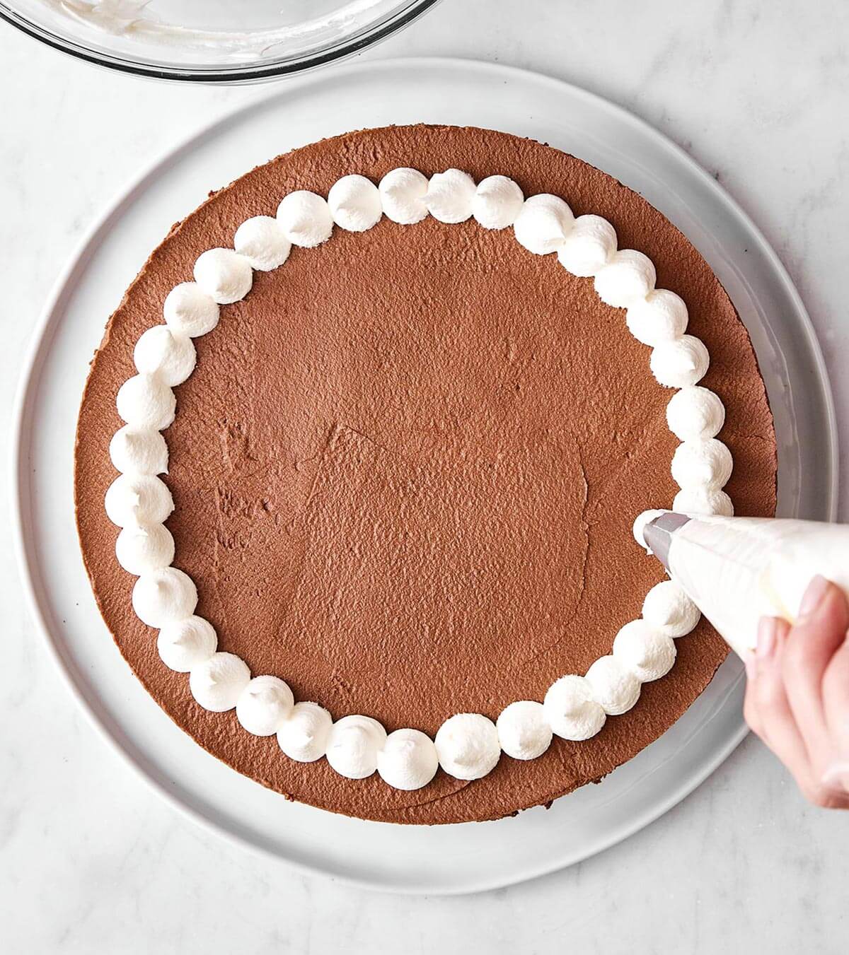 Adding whipped cream topping on a cake.