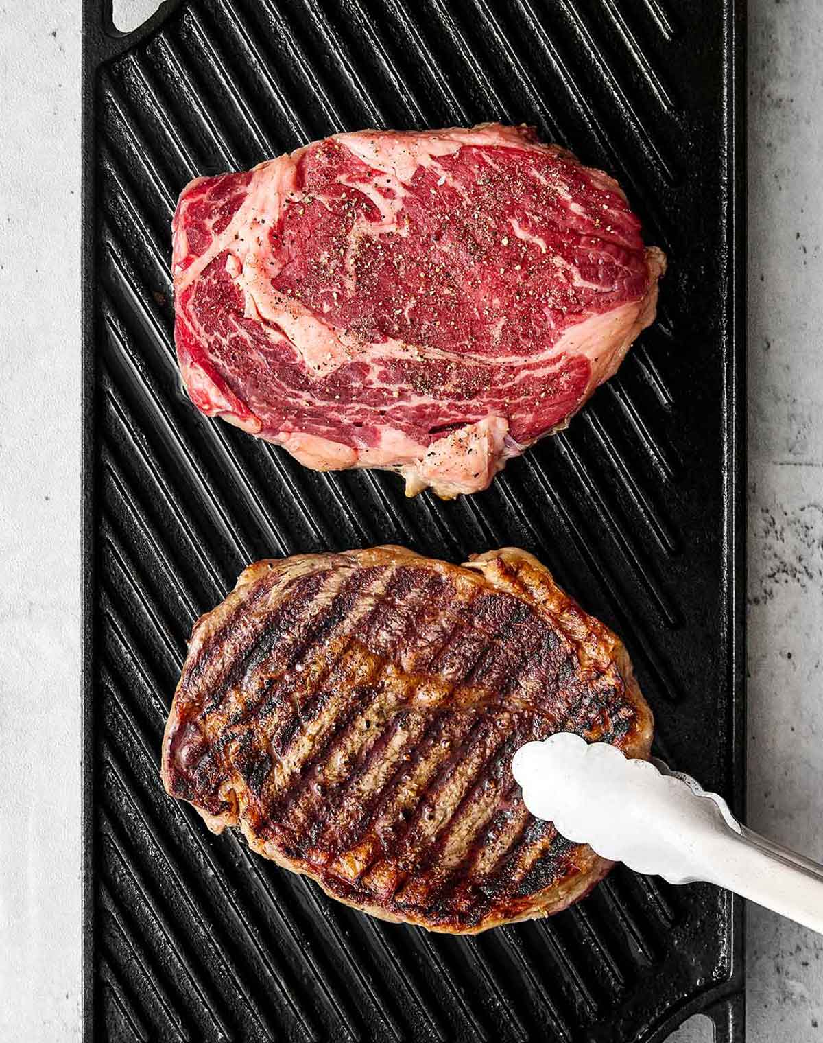 After testing different grill temperatures and timing, this is the grilled ribeye steak recipe I always come back to for a juicy medium-rare! Grilling ribeye steaks on a grill pan.