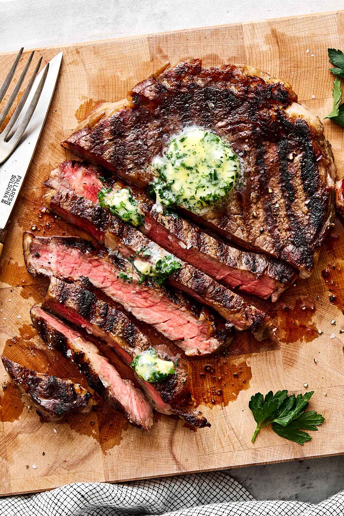 After testing different grill temperatures and timing, this is the grilled ribeye steak recipe I always come back to for a juicy medium-rare! Grilled ribeye steak on a wooden board.
