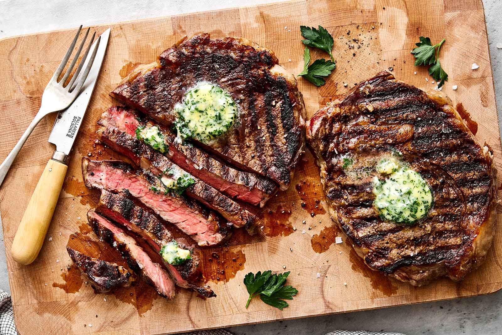 Sliced grilled ribeye steaks on a wooden board.