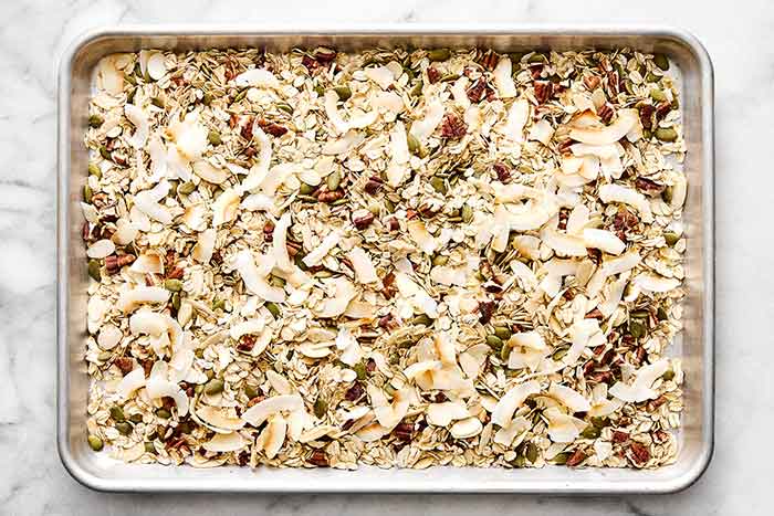 Toasting coconut flakes with muesli ingredients on a sheet pan.