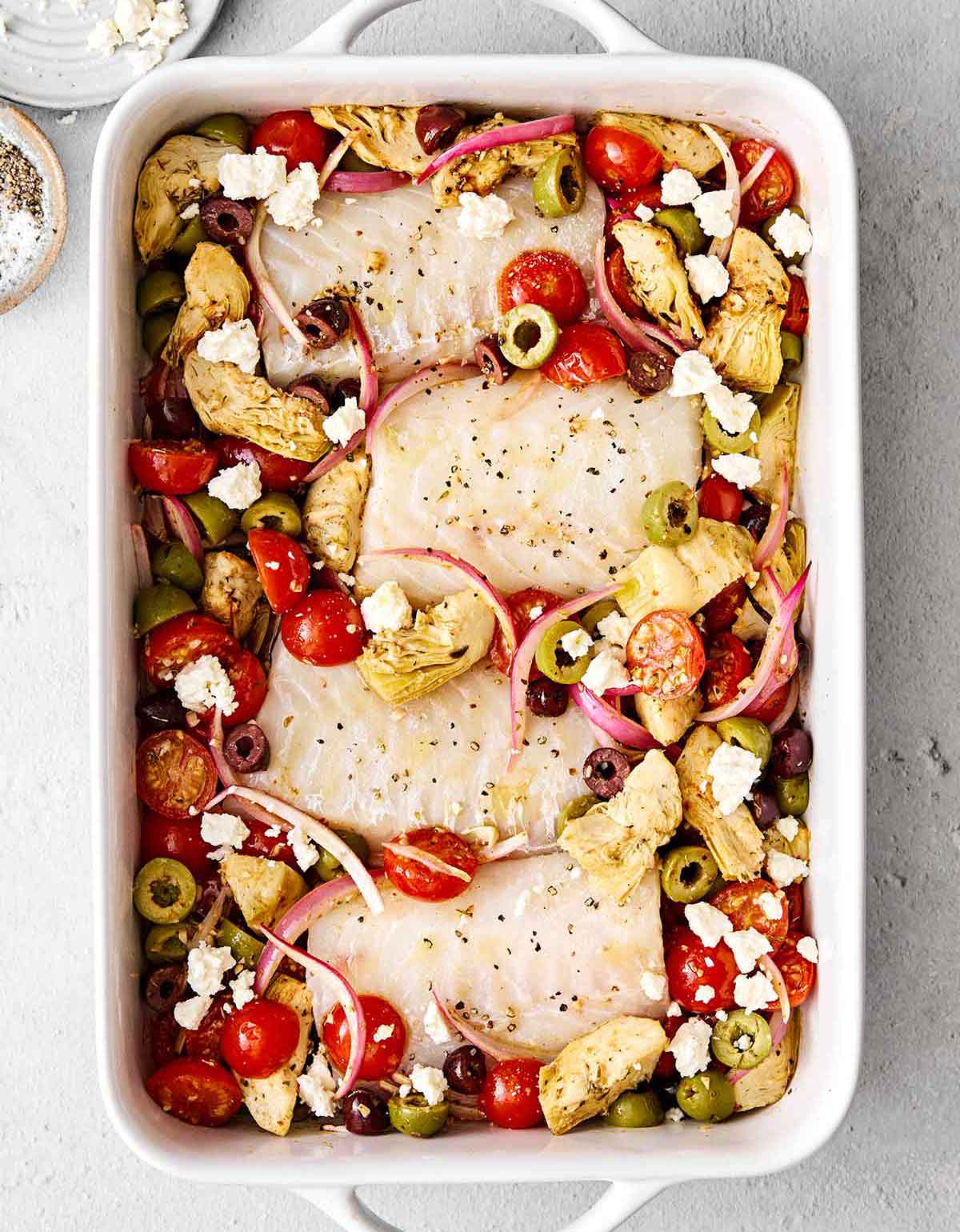 This Greek baked cod is the perfect all-in-one Mediterranean dinner! It's healthy, easy, and delicious! Baking cod and vegetables in a casserole pan.