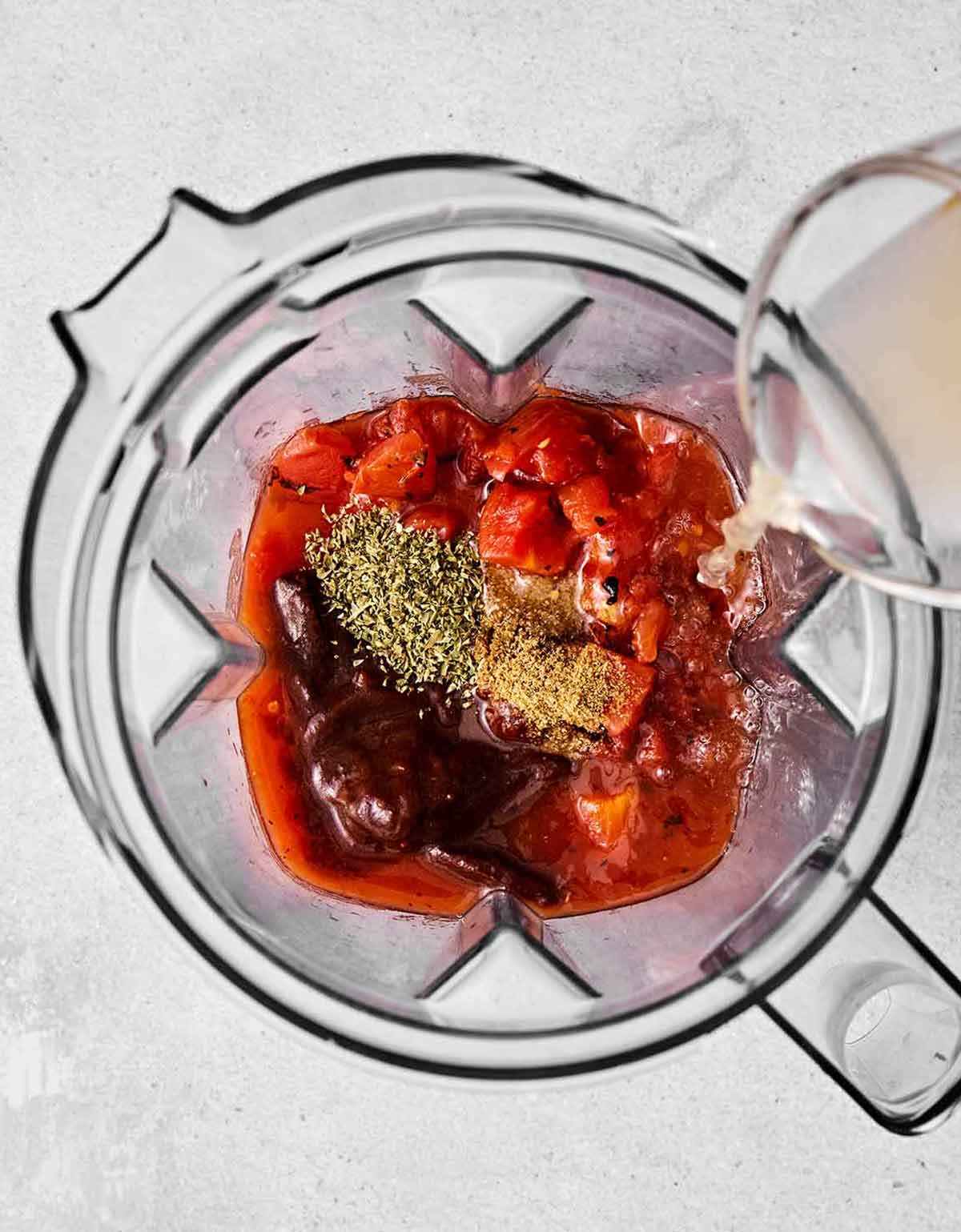 Blending chicken tinga sauce in a blender.
