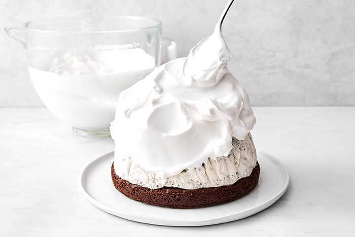 Adding the meringue on top of the ice cream layer for a baked Alaska.