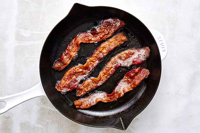 Cooking bacon in a pan for a wedge salad.