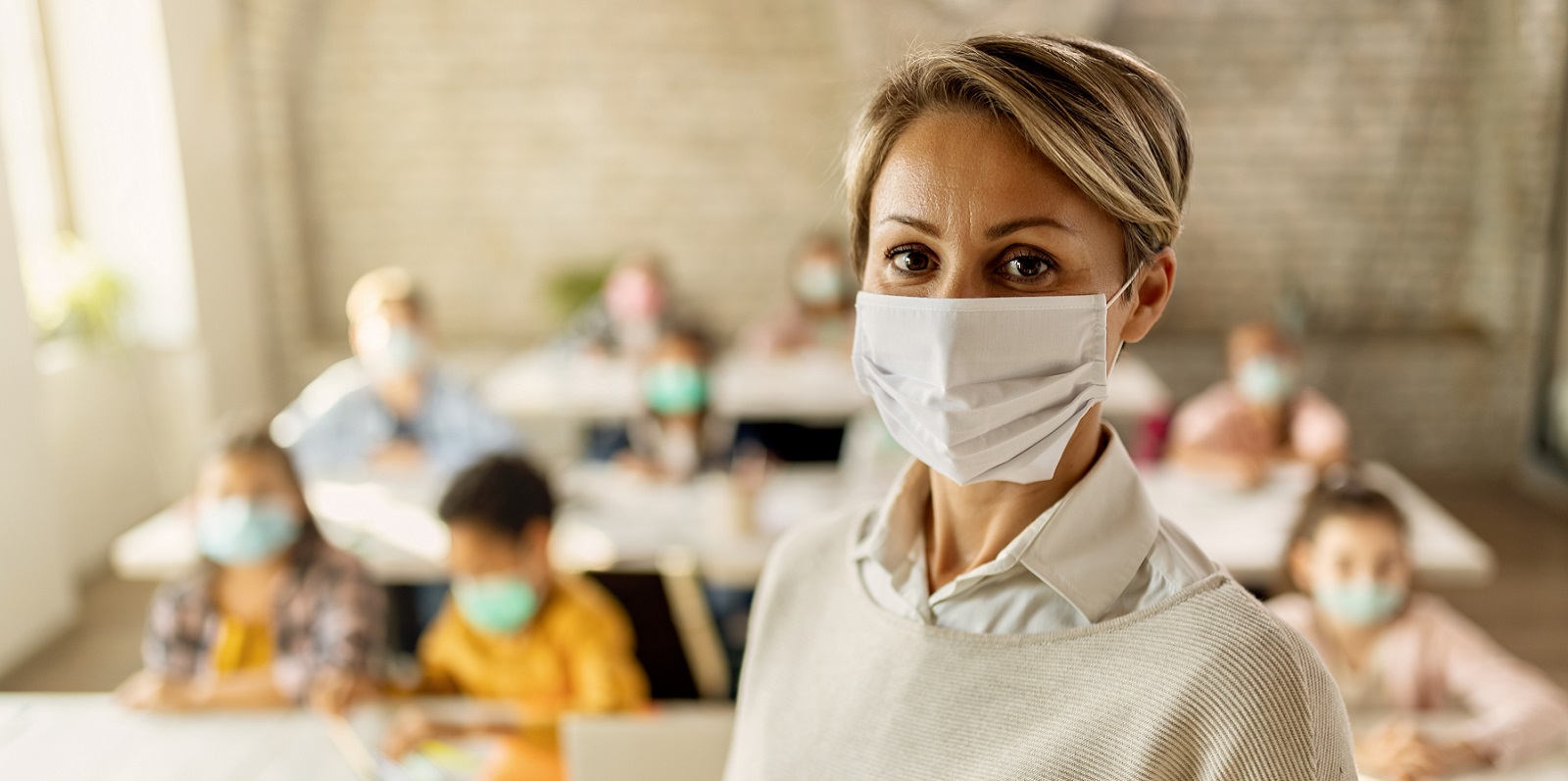 Elementary school teacher with protective face mask in the classroom