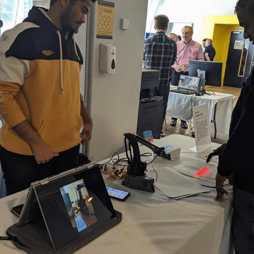 computer science end of year showcase. student talking to employer across a table about their project.