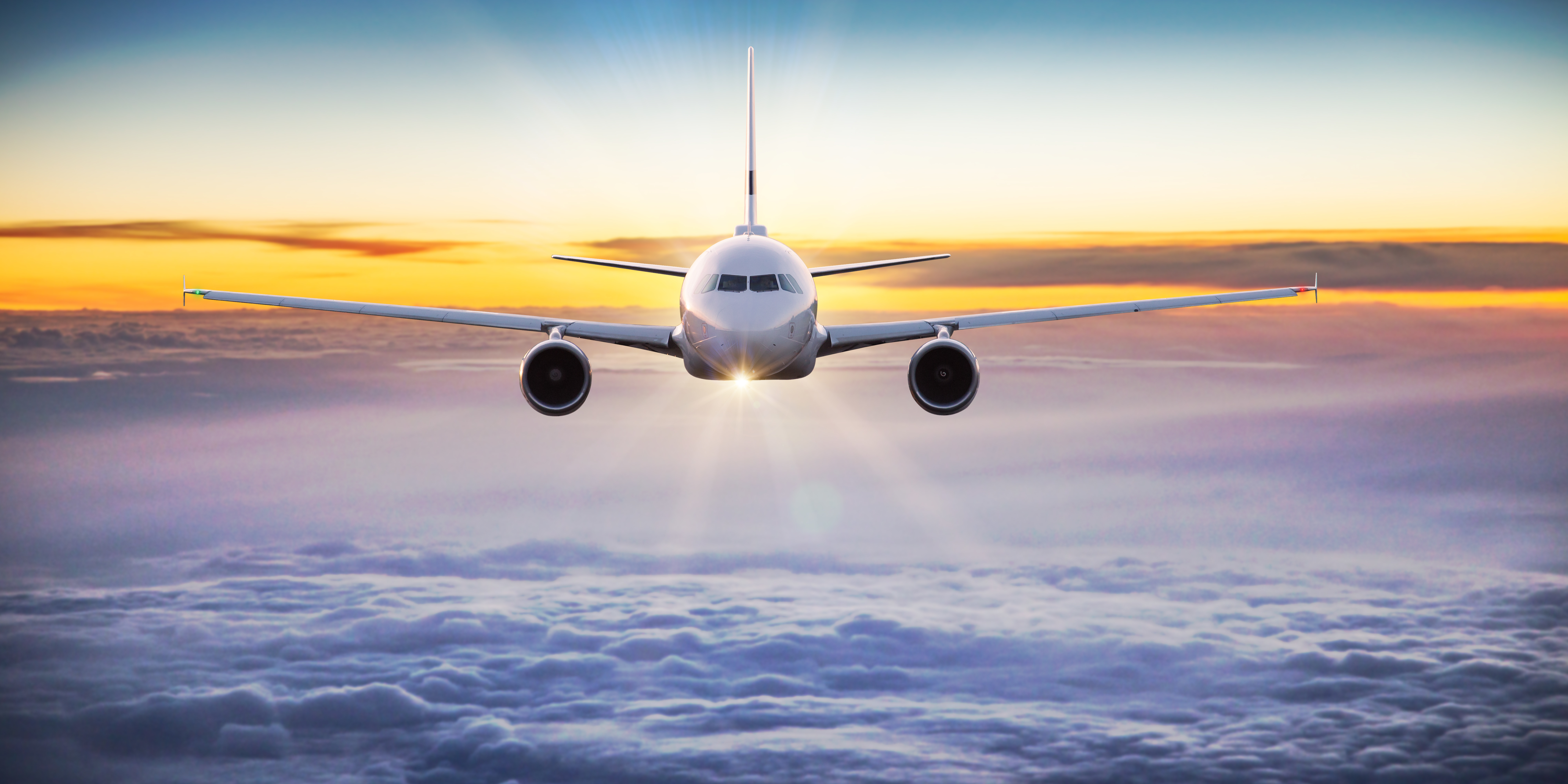 Commercial airplane flying above dramatic clouds during sunset. GTS