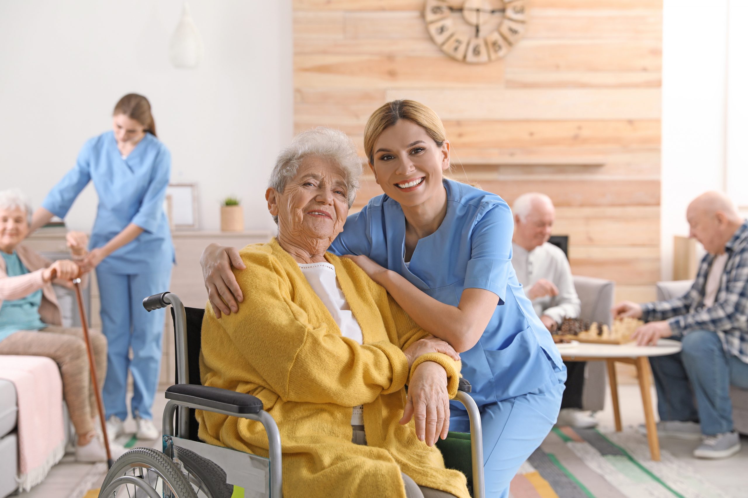 Nurse with elderly woman in wheelchair at retirement home. Assisting