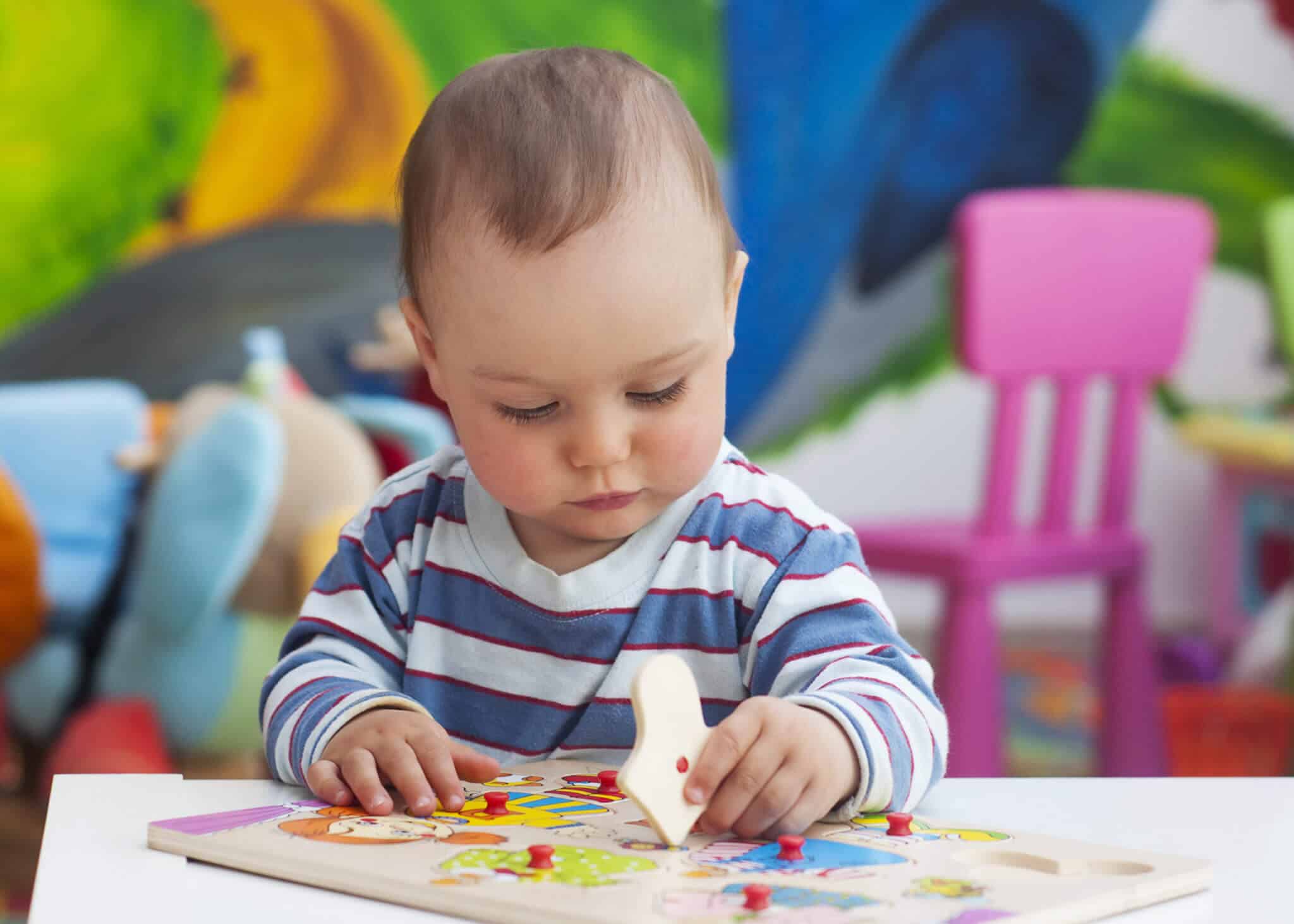 Toddler or a baby child playing with puzzle in a nursery. iCare
