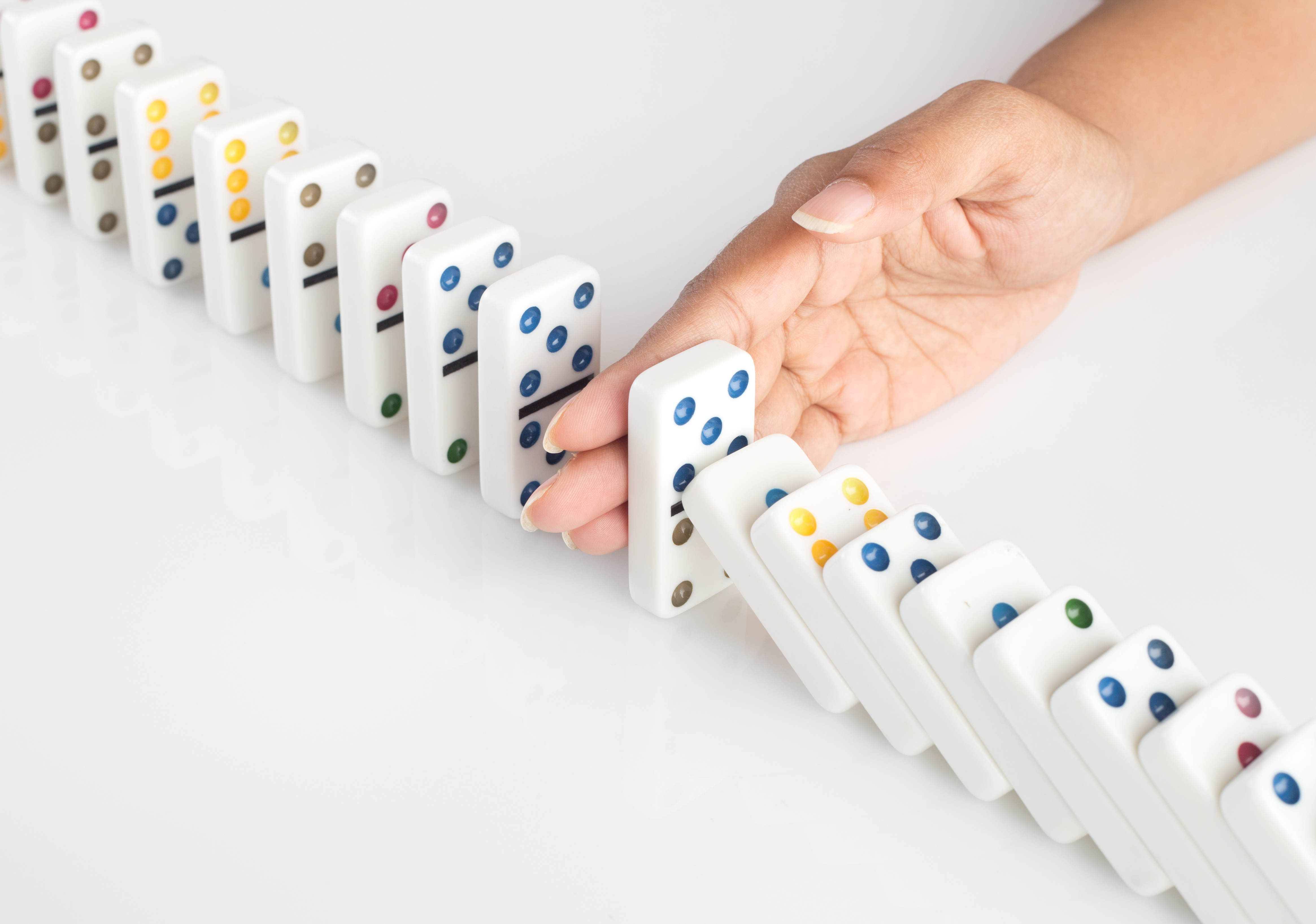 Hand stopping falling dominoes domino effect IT Exchange