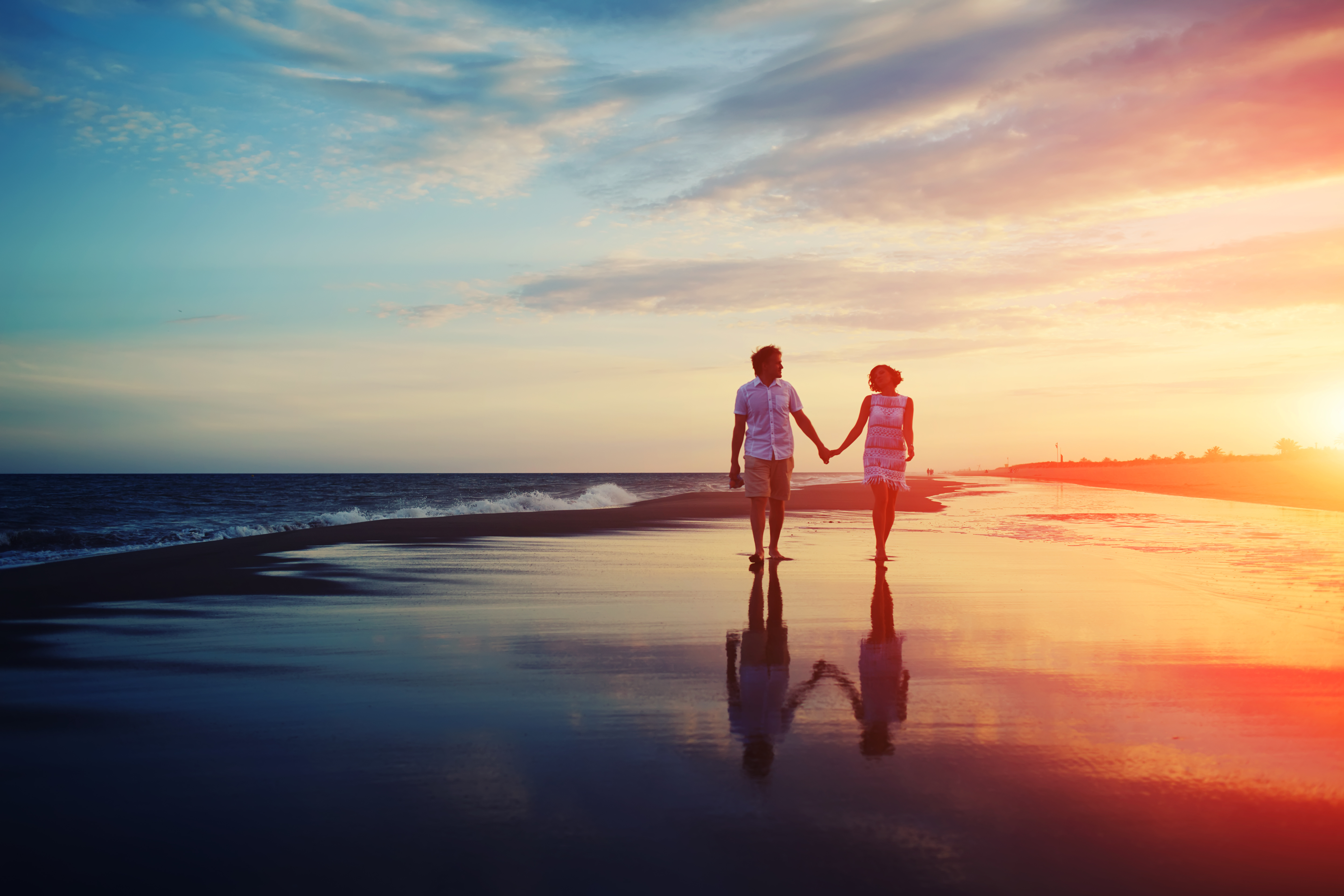 Happy romantic couple walking and holding hands on a beach