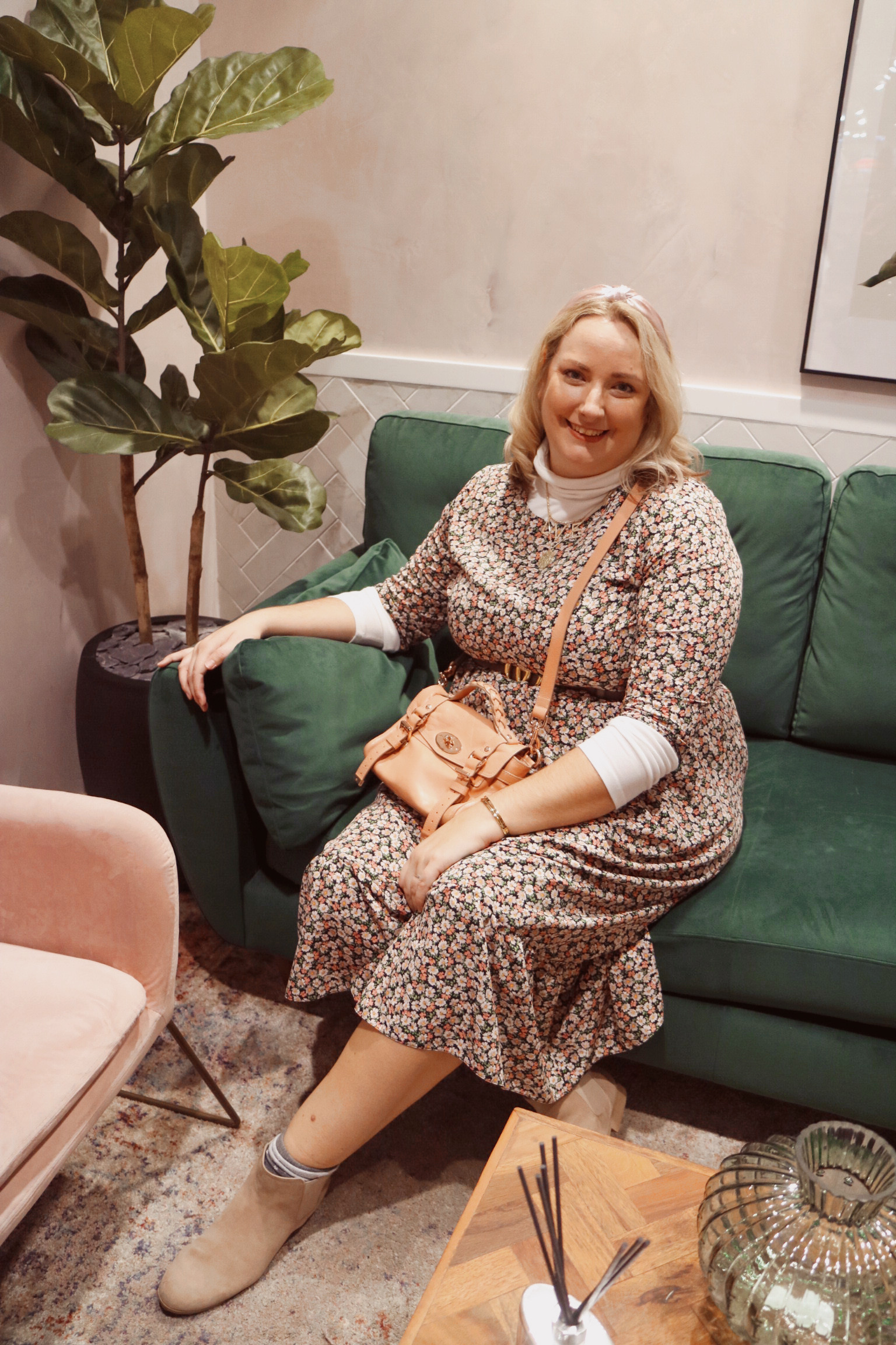 lucy in the floral dress sat on a green sofa