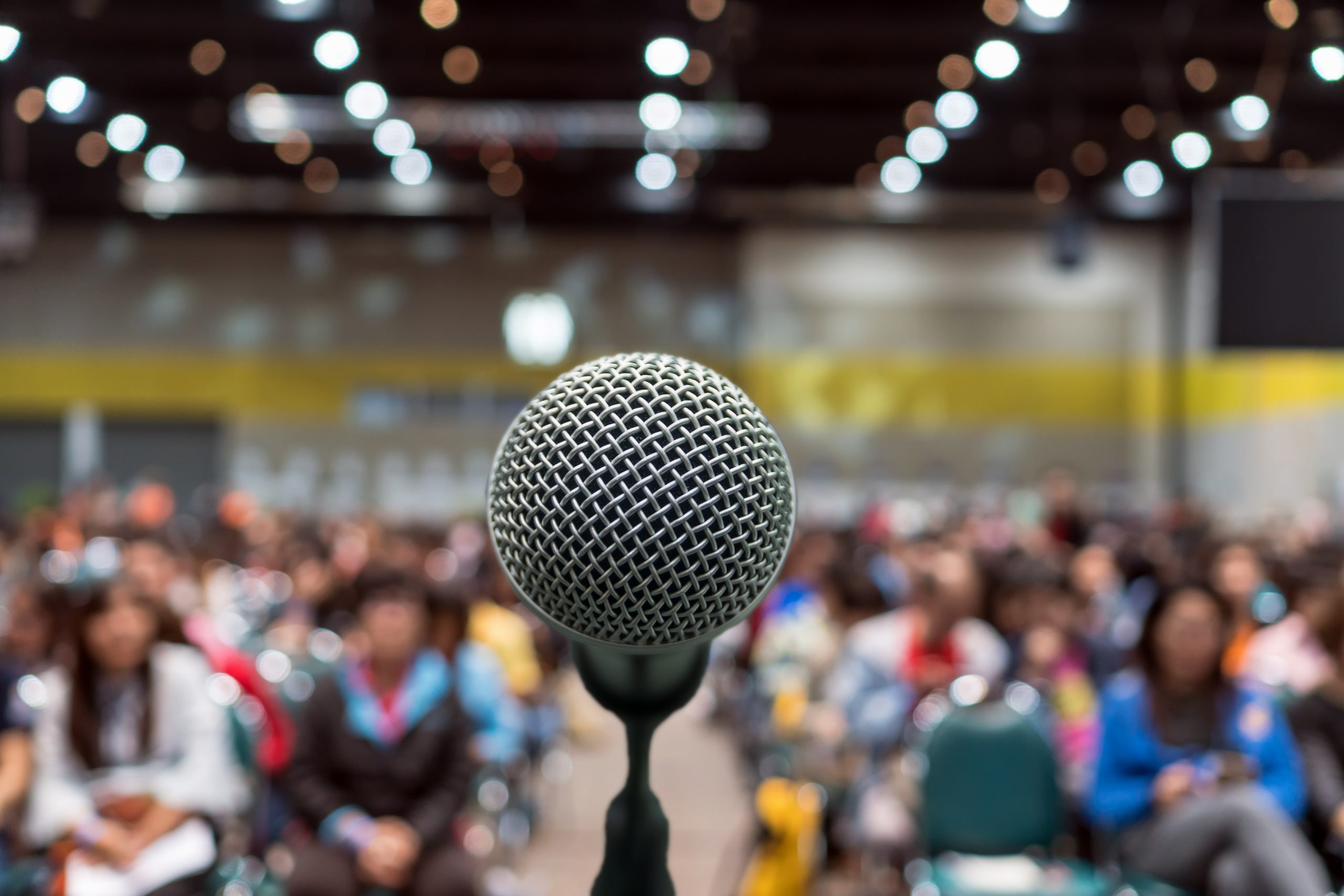 Microphone over the Abstract blurred photo of conference hall or