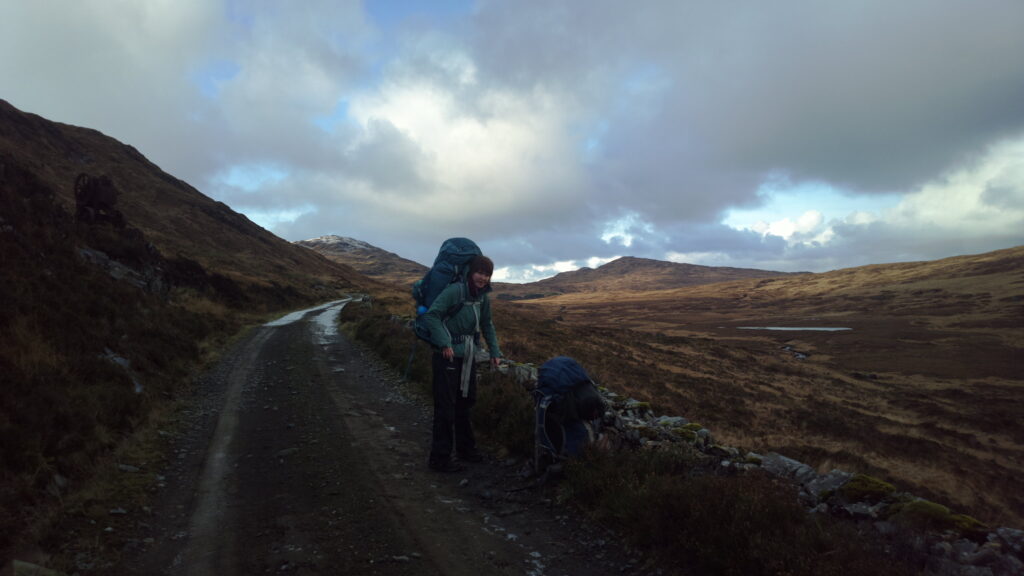 A backpacker walking on a road on Rùm, Scotland in winter time