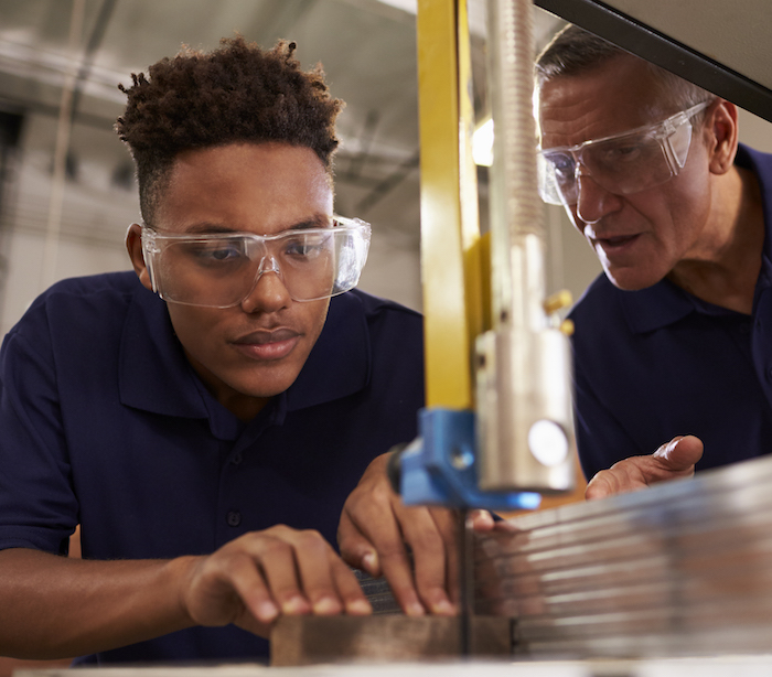 Carpenter Training Male Apprentice To Use Mechanized Saw New England