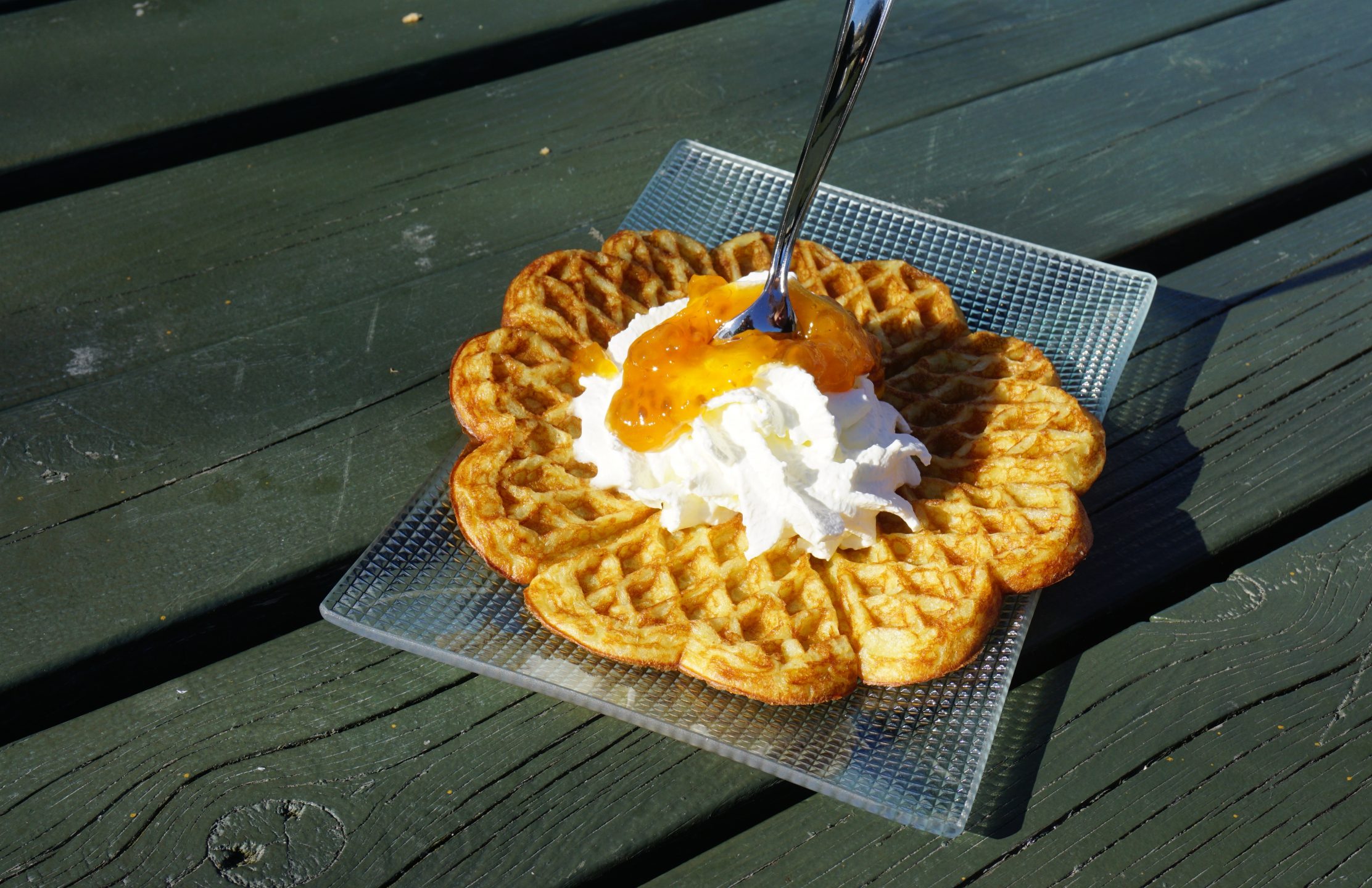 A Norwegian heartshaped waffle with whipped cream and cloudberry jam