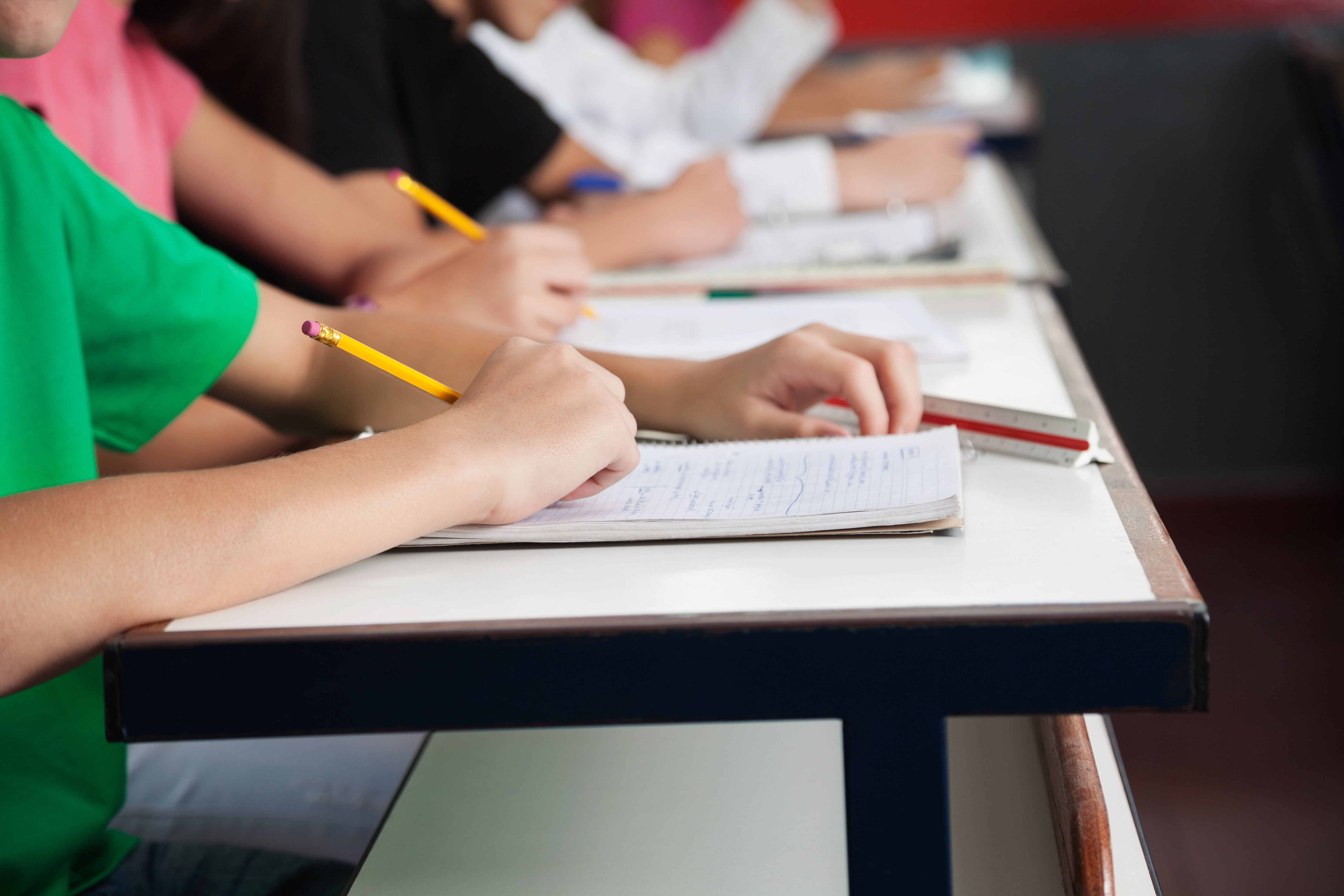 High School Students Writing On Paper At Desk — OSTAAECO