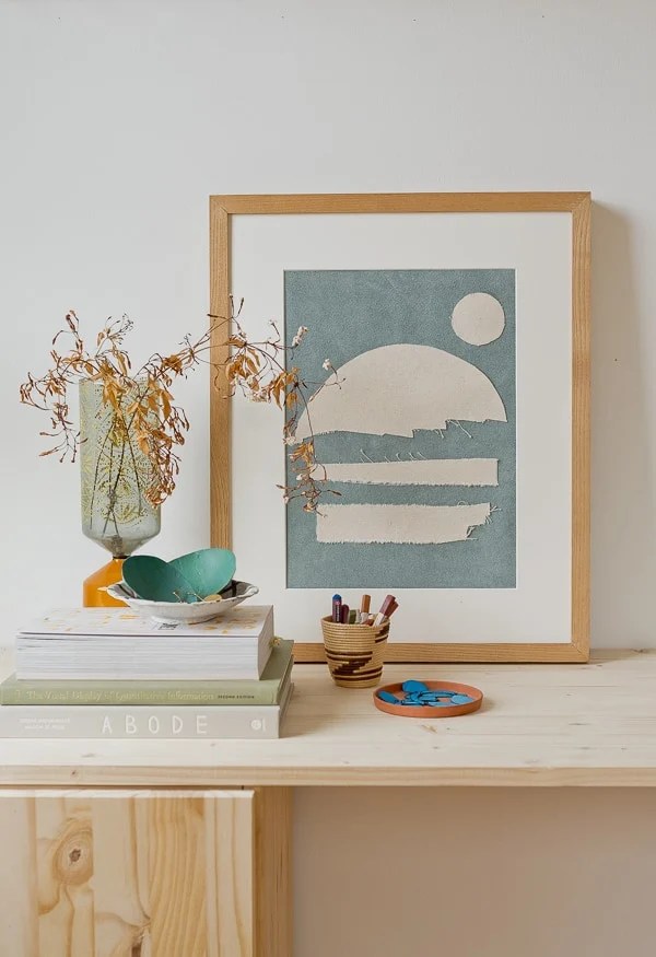 Modern abstract artwork made from scraps of canvas cut into small shapes to create a design, placed on a wooden desk.