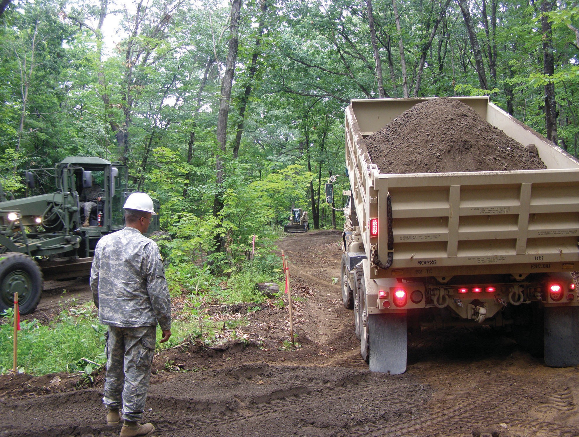 A member of the 185th Engineering Support Company of the 133rd Engineering Battalion of the Maine Army National Guard watches as a another guard member delivers a load of dirt to a portion of Sanford’s trail system. The national guard arrived in Sanford July 31, and will depart Sunday after crating 2,900 feet of trail.