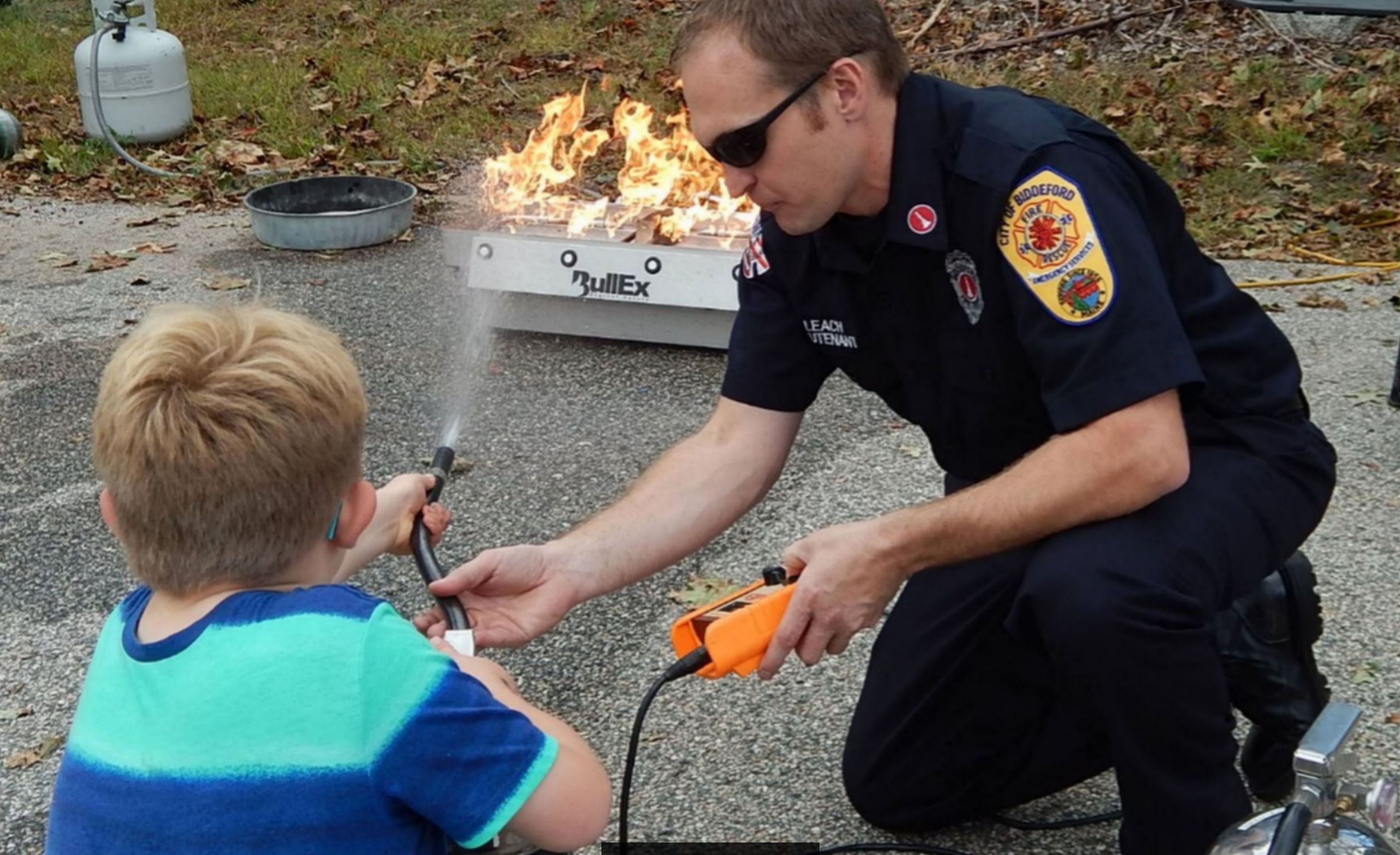 Biddeford Fire Department Lt. Matthew Leach shows a student how to properly use a fire extinguisher during the fire department's annual open house held at the Biddeford Fire Station on Saturday. ED PIERCE/Journal Tribune