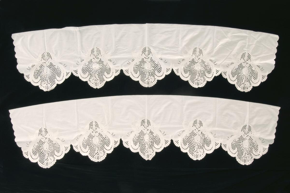 A pair of white valances with sewing machine embroidery